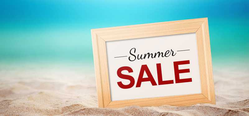 A sign saying "Summer Sale" resting on a beach