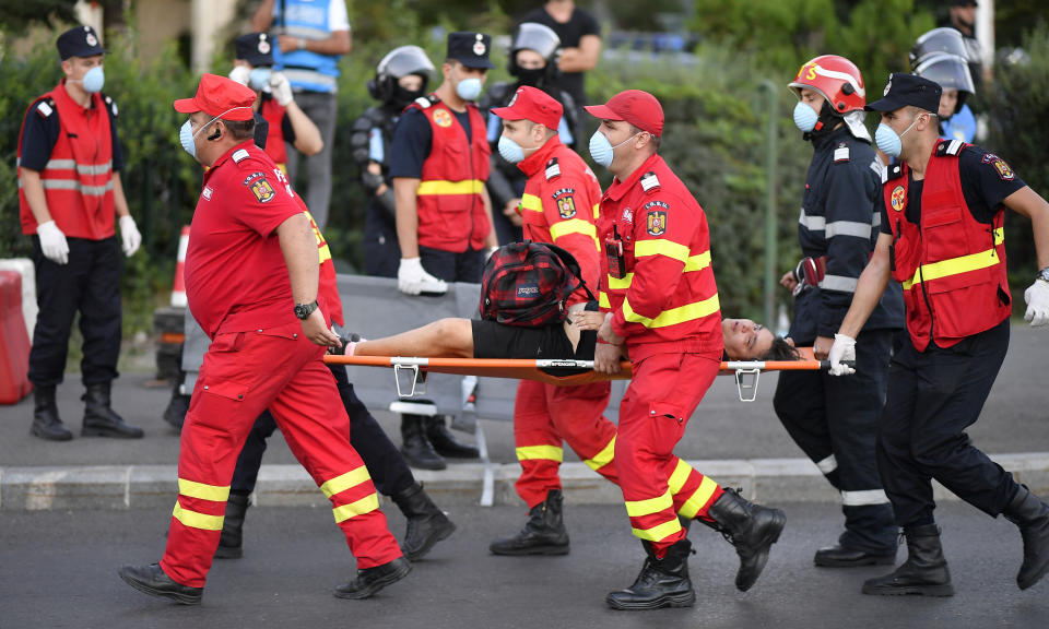 In this Friday, Aug. 10, 2018, photo, medical staff evacuate an injured person during protests outside the government headquarters in Bucharest, Romania. Romanian authorities say hundreds of people including two dozen riot police have received medical treatment after an anti-government protest turned violent and two weapons were stolen from riot police officers. (AP Photo/Raed Krishan)