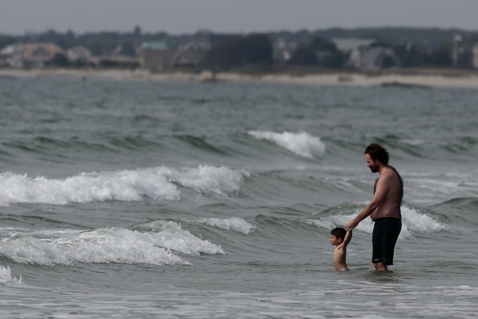A man and a small boy, keep their eyes on the rolling waves as they make their way onto the beach at Horseneck Beach in Westport.