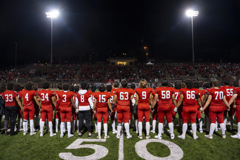 The Lahainaluna High School football team sings the alma mater in Hawaiian before their homecoming game at Sue D. Cooley Stadium, Saturday, Oct. 21, 2023, in Lahaina, Hawaii. Lahainaluna’s varsity and junior varsity football teams are getting back to normal since the devastating wildfire in August. (AP Photo/Mengshin Lin)