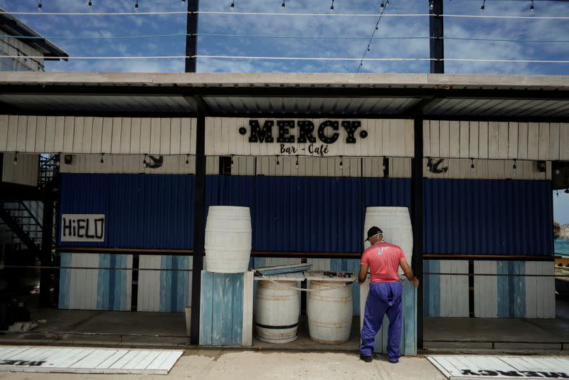 A worker removes a fence from a bar in anticipation of the Tropical Storm Laura arrival, in Havana