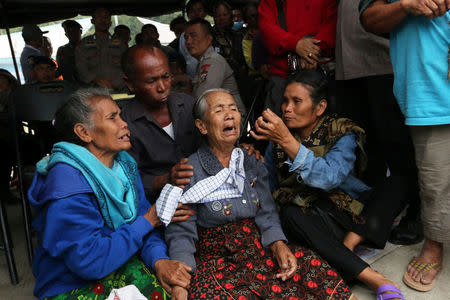 Relatives of missing passengers from a ferry accident on Lake Toba wait for news at a command post at Tigaras port in Simalungun, North Sumatra, Indonesia June 21, 2018, in this photo taken by Antara Foto. Antara Foto/Irsan Mulyadi/ via REUTERS