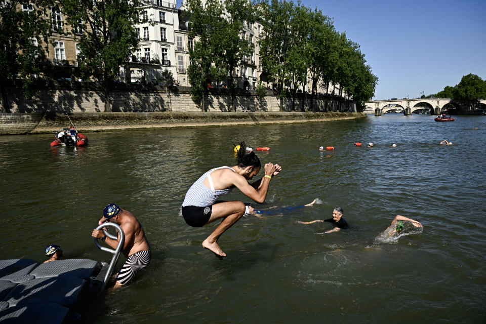 TOPSHOT - A local resident dives in the Seine, in Paris on July 17, 2024, after the mayor of Paris  swim in the river to demonstrate that it is clean enough to host the outdoor swimming events at the Paris Olympics later this month. Despite an investment of 1.4 billion euros ($1.5 billion) to prevent sewage leaks into the waterway, the Seine has been causing suspense in the run-up to the opening of the Paris Games on July 26 after repeatedly failing water quality tests. But since the beginning of July, with heavy rains finally giving way to sunnier weather, samples have shown the river to be ready for the open-water swimming and triathlon -- and for 65-year-old Hidalgo. (Photo by JULIEN DE ROSA / AFP) (Photo by JULIEN DE ROSA/AFP via Getty Images)