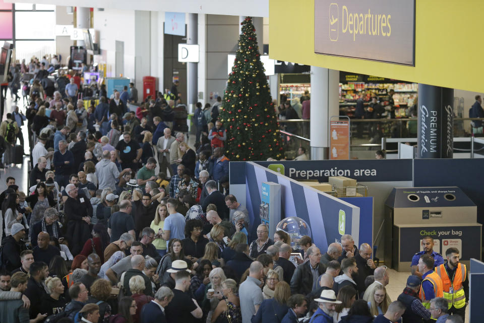 People wait near the departures gate at Gatwick airport, near London, as the airport remains closed with incoming flights delayed or diverted to other airports, after drones were spotted over the airfield last night and this morning, Thursday, Dec. 20, 2018. London's Gatwick Airport remained shut during the busy holiday period Thursday while police and airport officials investigate reports that drones were flying in the area of the airfield. (AP Photo/Tim Ireland)