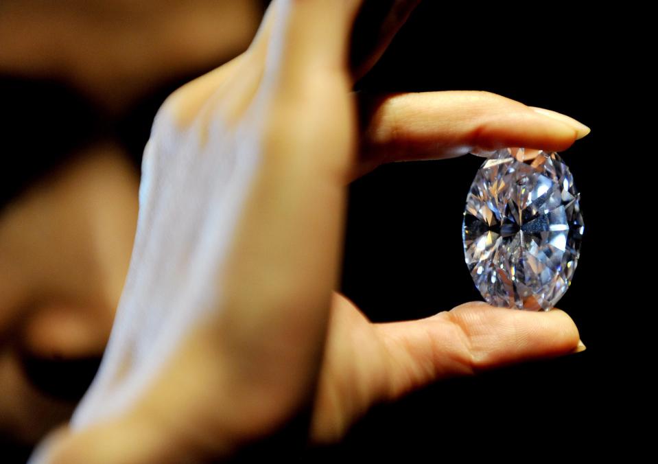 A Sotheby's employee holds the white diamond at 118.28 carats, the largest D colour Flawless diamond, estimated between £18-22 million, during a preview of the auction house's forthcoming London Rocks sale in October, when two diamonds, the white diamond and the worlds largest round fancy vivid blue diamond, a 7.59 Carat stone, estimated in excess of £12 million, are expected to fetch over £30 million between them at the sale.