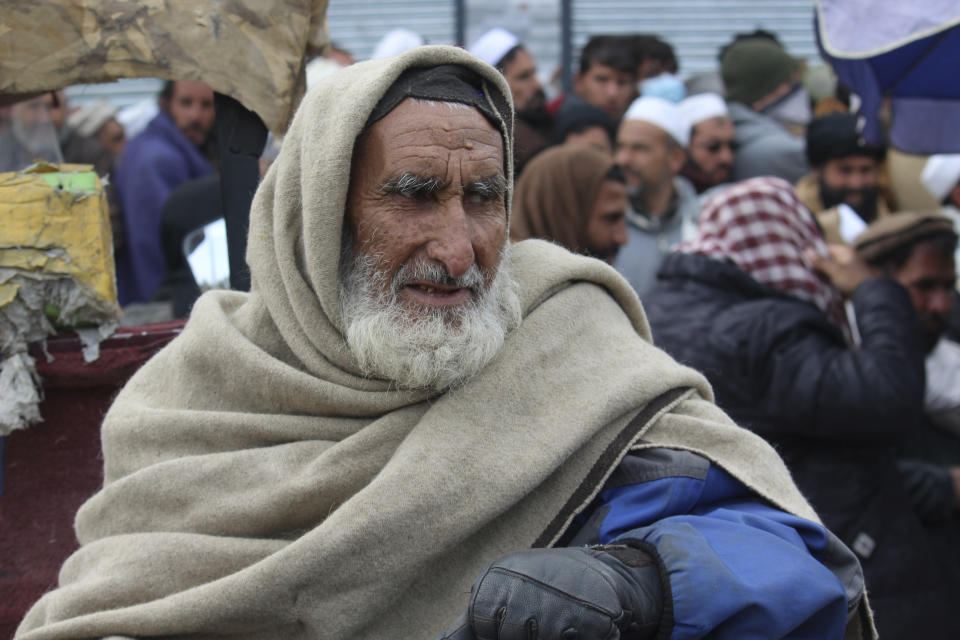 Afghans wait to receive food rations organized by the World Food Program (WFP) in Pul-e-Alam, the capital of Logar province. eastern of Afghanistan, Tuesday, Jan. 18, 2022. The Taliban's sweep to power in Afghanistan in August drove billions of dollars in international assistance out of the country and sent an already dirt-poor poor nation, ravaged by war, drought and floods, spiralling toward a humanitarian catastrophe. (AP Photo/Zubair Abassi)