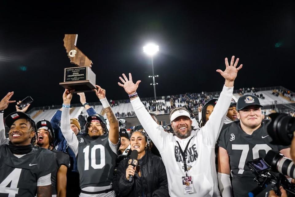 Louisville football signee Pierce Clarkson, middle, hoists the California Open Division championship trophy into the air with fellow signee Aaron Williams, far left, and other members of the St. John Bosco High School football team on Saturday, Dec. 10, 2022.