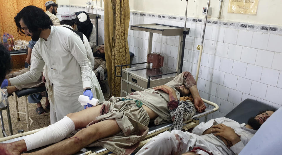 A Pakistani paramedic treats men, who were injured in a fighting between Afghan security forces and Taliban in Spin Boldak border area, at a hospital in Chaman, Pakistan, Friday, July 16, 2021. Afghan government security forces were battling to retake the southeastern Spin Boldak border crossing with neighbor Pakistan Friday, according to Afghanistan's deputy defense ministry spokesman Fawad Awan. (AP Photo/Tariq Achakzai)