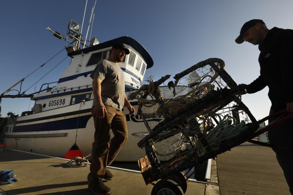 Fishermen move crab pots on the docks in Crescent City marina