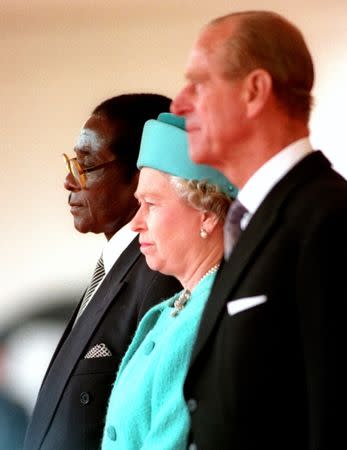 Queen Elizabeth II and the Duke of Edinburgh stand with the President of Zimbabwe, Robert Mugabe (L), shortly before he reviewed a guard of honour in London May 17, 1994. REUTERS/Kevin Coombs/Files
