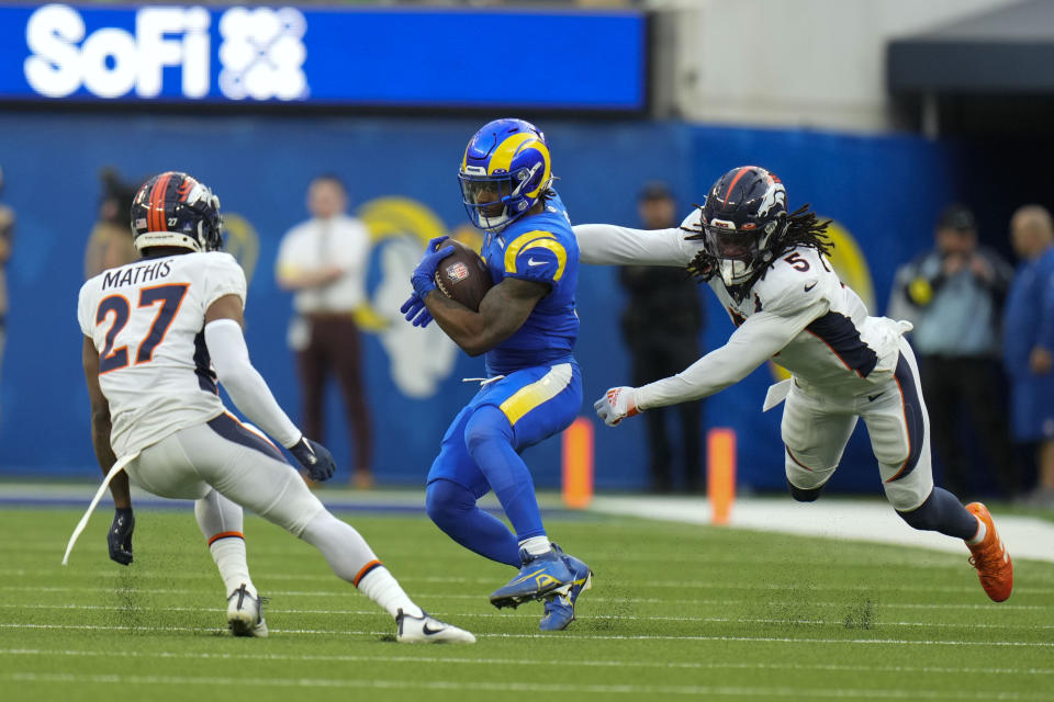 Los Angeles Rams running back Cam Akers runs between Denver Broncos cornerback Damarri Mathis, left, and linebacker Randy Gregory during the first half of an NFL football game between the Los Angeles Rams and the Denver Broncos on Sunday, Dec. 25, 2022, in Inglewood, Calif. (AP Photo/Jae C. Hong)