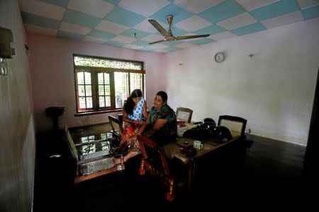 A family sits on a table inside their flooded house in Nagoda village in Kalutara, Sri Lanka May 29, 2017. REUTERS/Dinuka Liyanawatte