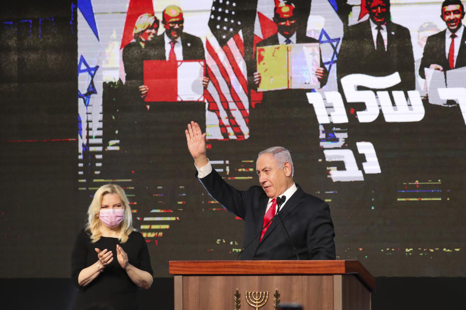 Israeli Prime Minister Benjamin Netanyahu with his wife Sara Netanyahu waves to his supporters after the first exit poll results for the Israeli parliamentary elections at his Likud party's headquarters in Jerusalem, Wednesday, March. 24, 2021. (AP Photo/Ariel Schalit)