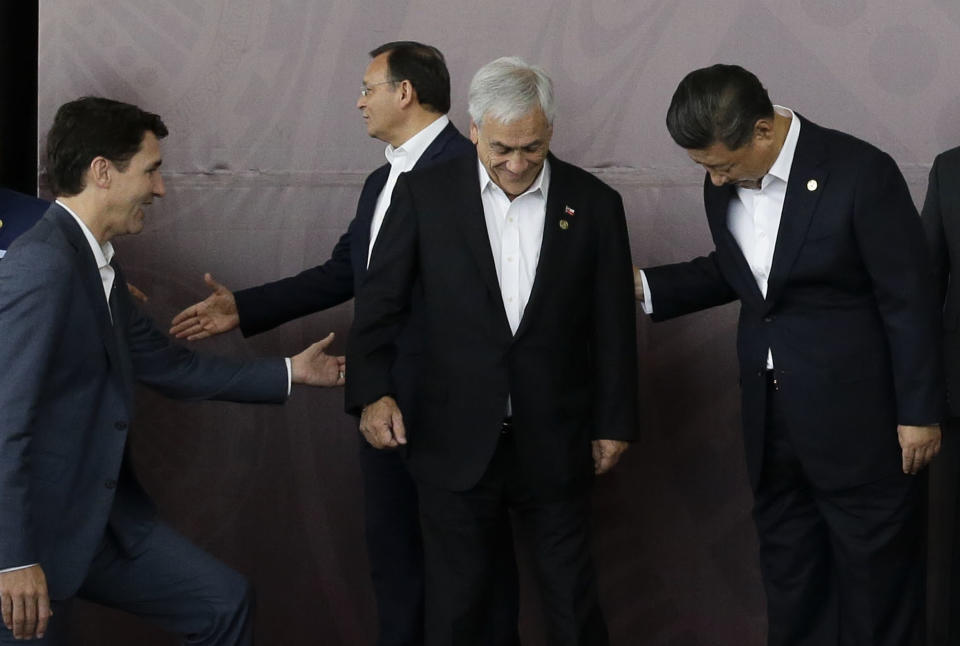 Canada Prime Minister Justin Trudeau, left, and Chinese President Xi Jinping, right, help Chilean President Sebastian Pinera, center, during the family photo at the APEC Economic Leaders Meeting at Port Moresby, Papua New Guinea on Sunday, Nov. 18, 2018. (AP Photo/Aaron Favila)