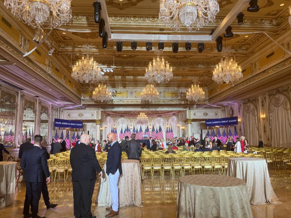 People in suits standing around a large gold ballroom with gold chairs