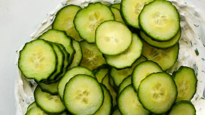 sliced unpeeled cucumbers atop sauce