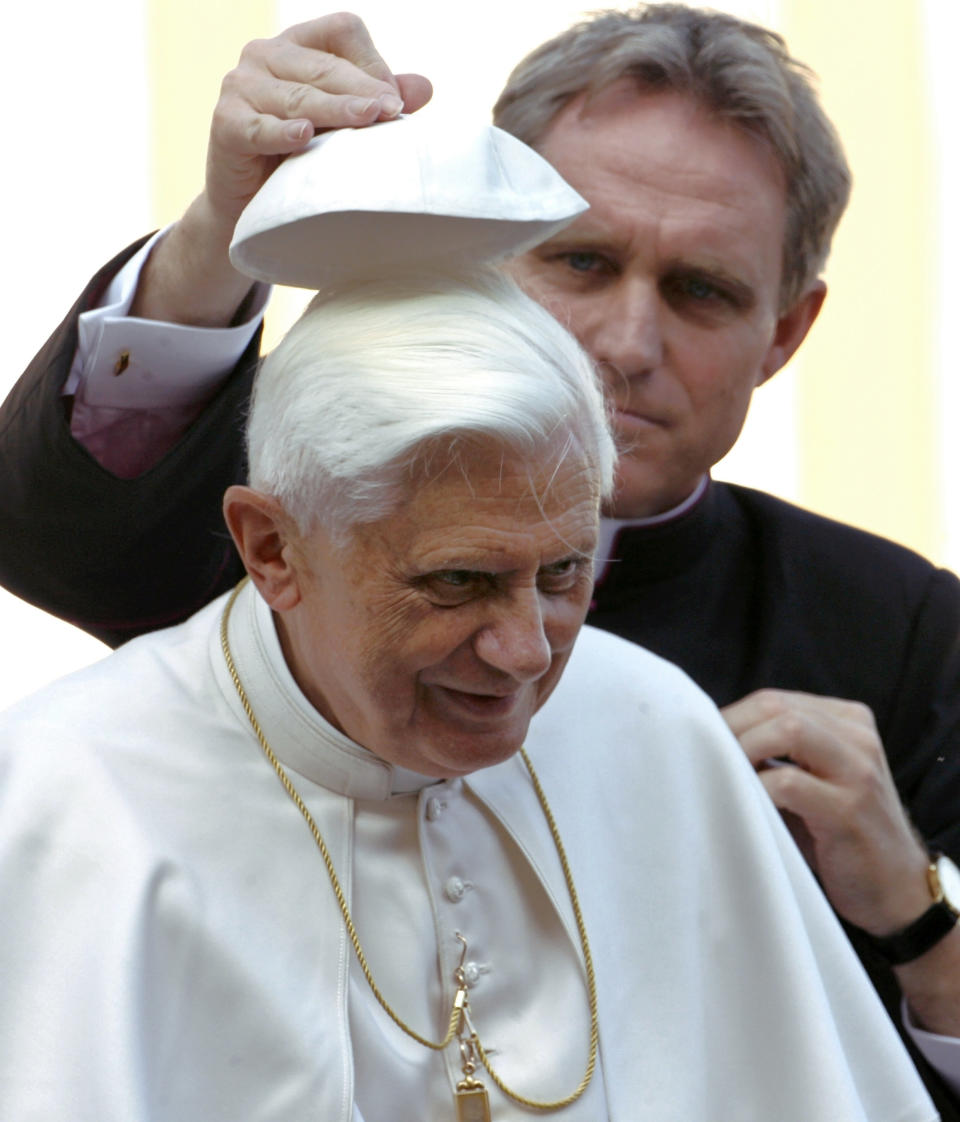 FILE - Rev. Georg Gaenswein, back, helps put a cap on Pope Benedict XVI's head at the end of the pontiff's weekly general audience in St. Peter's Square at the Vatican, on Oct. 25, 2006. When Cardinal Joseph Ratzinger became Pope Benedict XVI and was thrust into the footsteps of his beloved and charismatic predecessor, he said he felt a guillotine had come down on him. The Vatican announced Saturday Dec. 31, 2022 that Benedict, the former Joseph Ratzinger, had died at age 95. (AP Photo/Andrew Medichini, File)