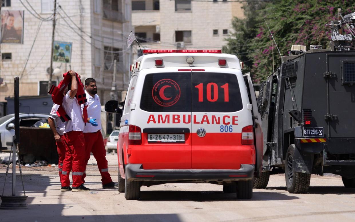 A worker of the Palestine Red Crescent Society takes off his vest as they are body-searched by the Israeli army