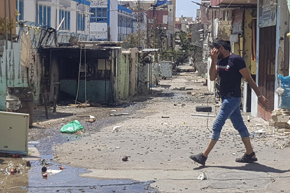 A man passes by houses riddled with bullets after the deadly clashes between Palestinian factions in the Palestinian refugee camp of Ein el-Hilweh near the southern port city of Sidon, Lebanon, Thursday, Aug. 3, 2023. The caretaker Lebanese prime minister called the Palestinian president on Thursday to demand an end to the volatile situation in Lebanon's largest Palestinian refugee camp, warning that the army may have to intervene to stop the days-long fighting that has left dozens dead and wounded. (AP Photo/Mohammad Zaatari)