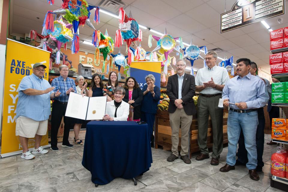 Gov. Laura Kelly holds up the food sales tax bill after signing it — for the fourth time — June 13 at Mi Pueblito Meat Market.