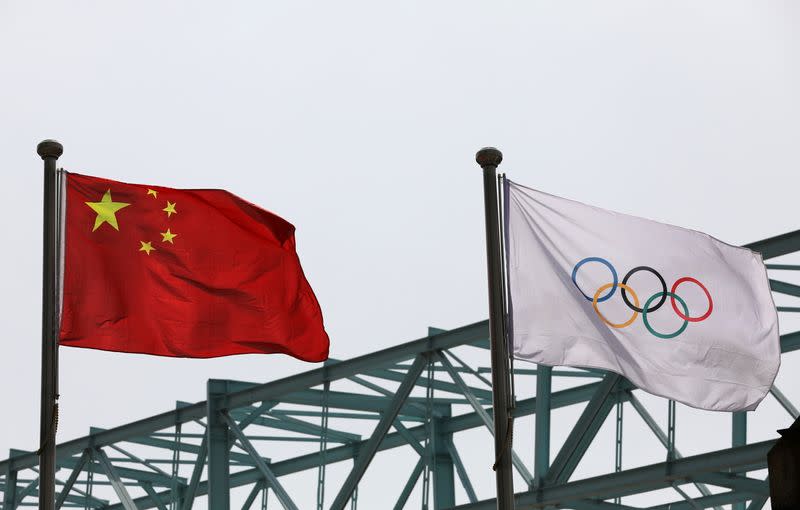 FILE PHOTO: Chinese national flag flutters next to an Olympic flag at the Beijing Organising Committee for the 2022 Olympic and Paralympic Winter Games, in Beijing