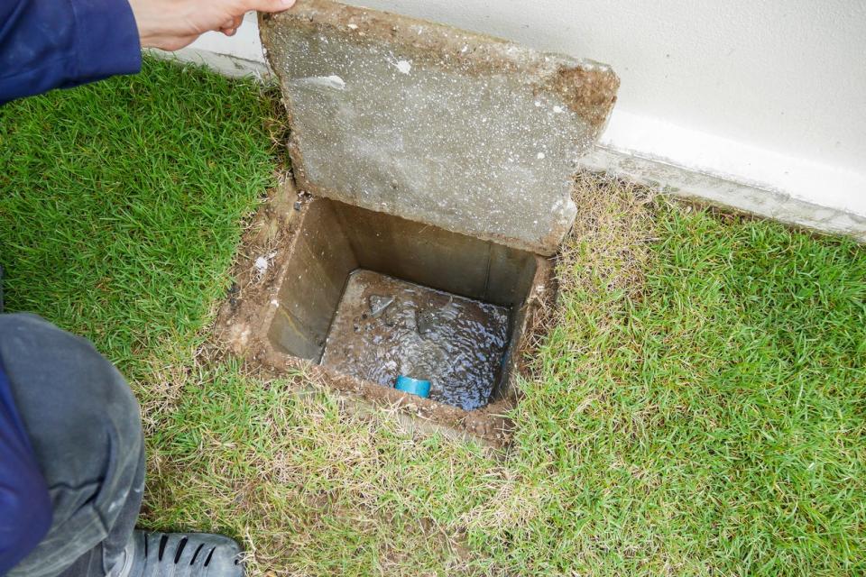 A close up of a hole in the lawn where plumbing is seen.