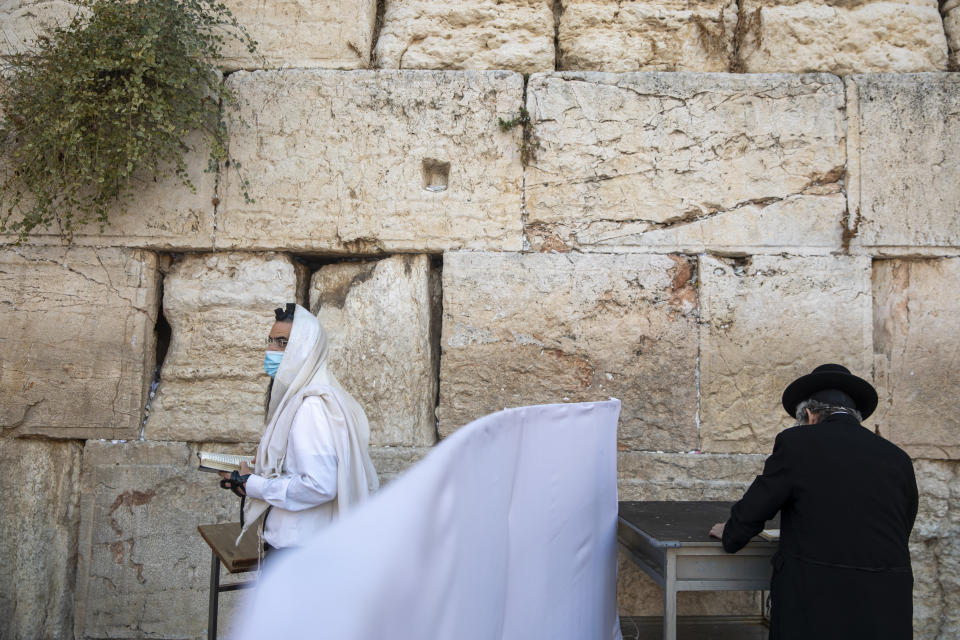 With social distancing barrier, ultra-Orthodox Jewish men pray ahead of Yom Kippur, the holiest day in the Jewish year, at the Western Wall, the holiest site where Jews can pray in Jerusalem's Old City, Sunday, Sept. 27, 2020. For Israel's ultra-Orthodox Jews, coronavirus restrictions have raised numerous questions about how to maintain their religious lifestyle during the outbreak. A religious publisher in Jerusalem released a book in July with over 600 pages of guidance from 46 different rabbis. (AP Photo/Ariel Schalit)