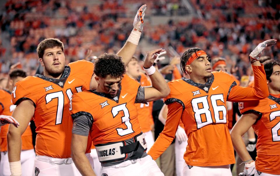 Oklahoma State's Spencer Sanders (3) sings the alma mater with Oklahoma State's Preston Wilson (74) and Cale Fulsom (86) during the college football game between the Oklahoma State University Cowboys and the University of Kansas Jayhawks at Boone Pickens Stadium in Stillwater, Okla., Saturday, Oct. 30, 2021. 