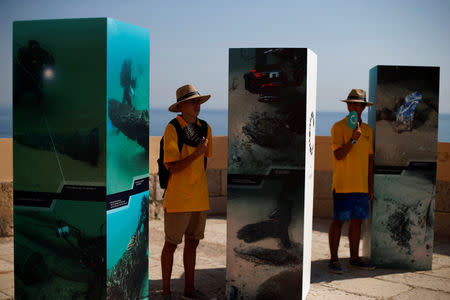 People pass by the pictures during a news conference regarding the announcement of the discovery of a centuries-old shipwreck, in Cascais, Portugal September 24, 2018. REUTERS/Pedro Nunes