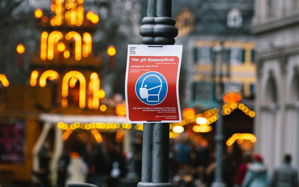 Face mask sign, Christmas market, Bonn, Germany - Getty