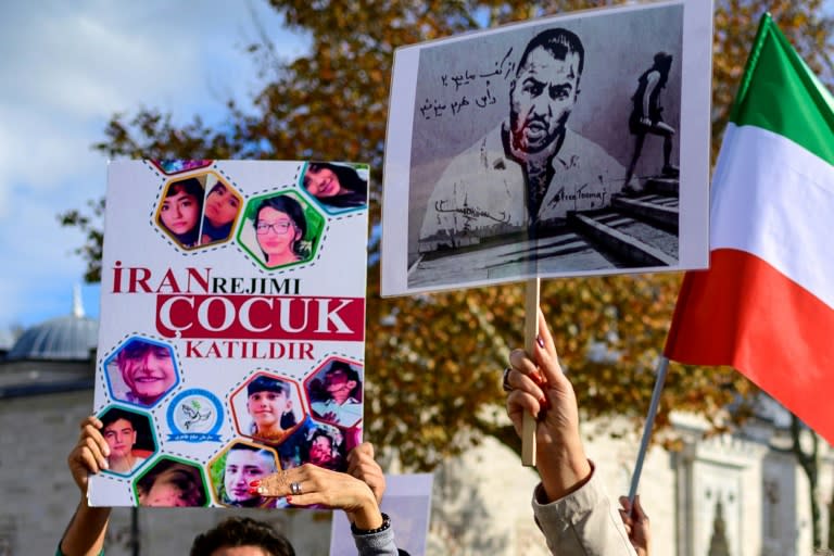 Un portrait du rappeur iranien Toomaj Salehi (d), et des portraits d'enfants tués lors des manifestations en Iran (g), au cours d'un rassemblement de soutien aux femmes iraniennes à Istanbul, le 26 novembre 2022 (Yasin AKGUL)