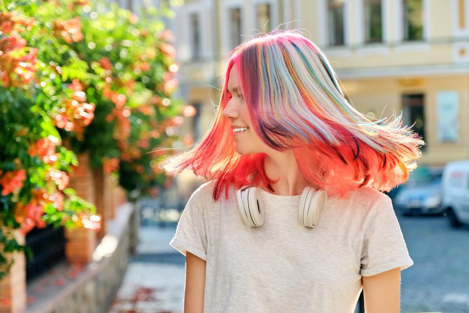 Hairstyles, hairs, fashion, trends, coloring. Close-up of fluttering colored dyed hair of young woman on sunny city street�