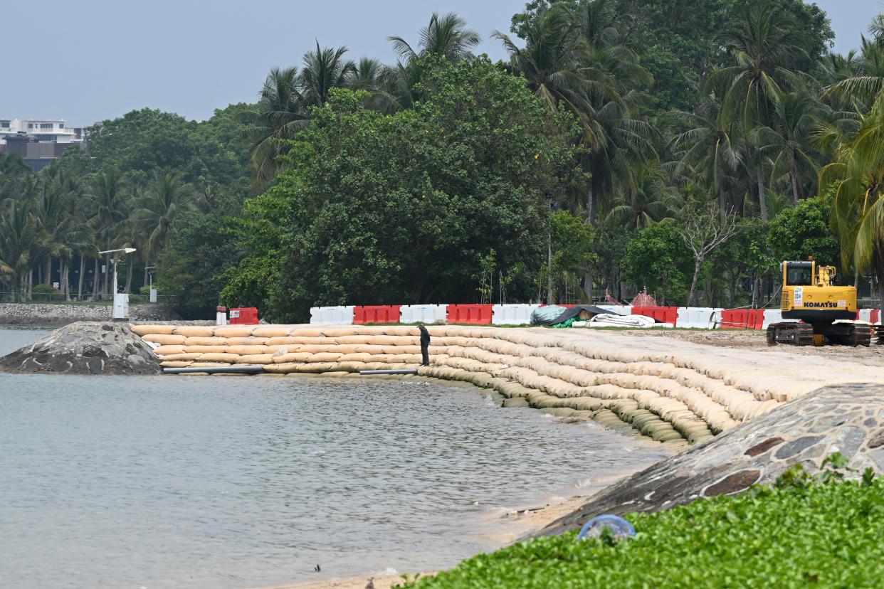 A worker stands on sandbags, laid along the shore to prevent erosion during high-tide periods, at a beach in Singapore on April 13, 2021. (PHOTO: AFP via Getty Images)