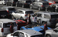 Students wait near their cars before a drive-thru graduation for Faith Lutheran High School at the Las Vegas Motor Speedway, Friday, May 22, 2020, in Las Vegas. The school held a special drive-thru graduation amid the coronavirus pandemic. (AP Photo/John Locher)