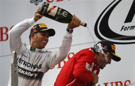 First-placed Mercedes Formula One driver Lewis Hamilton of Britain (L) pours champagne on third-placed Ferrari Formula One driver Fernando Alonso of Spain as he celebrates his win after the Chinese F1 Grand Prix at the Shanghai International Circuit April 20, 2014. REUTERS/Carlos Barria