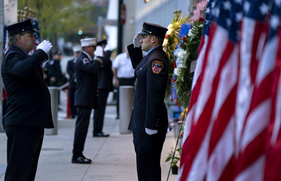 New York City firefighters salute in front of a memorial on the side of a firehouse adjacent to One World Trade Center and the 9/11 Memorial site during ceremonies on the 18th anniversary of 9/11 terrorist attacks in New York on Wednesday, Sept. 11, 2019. (AP Photo/Craig Ruttle)