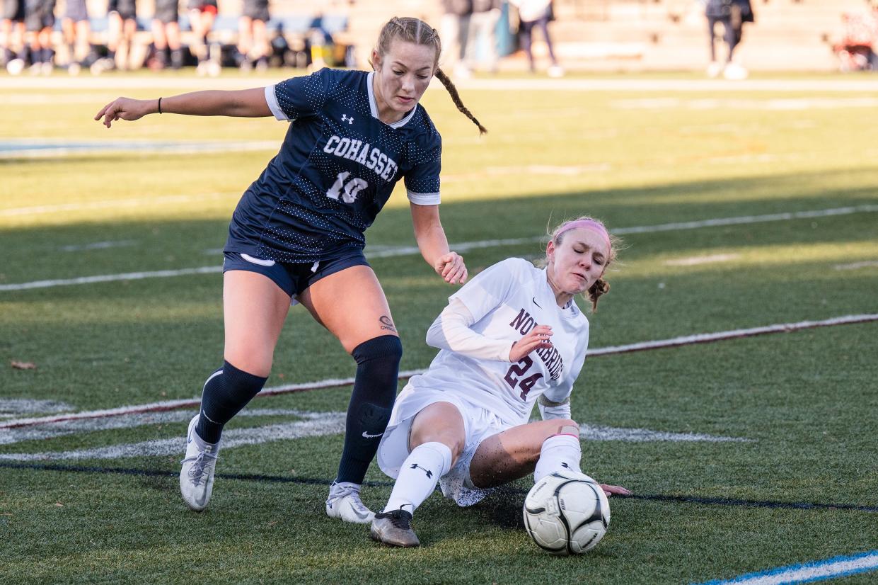 While Cohasset's Tess Barrett drives downfield, Northbridge's Keira Touhey comes in with a slide tackle.