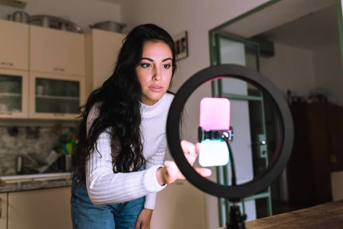 A girl looking into her phone on a ring light