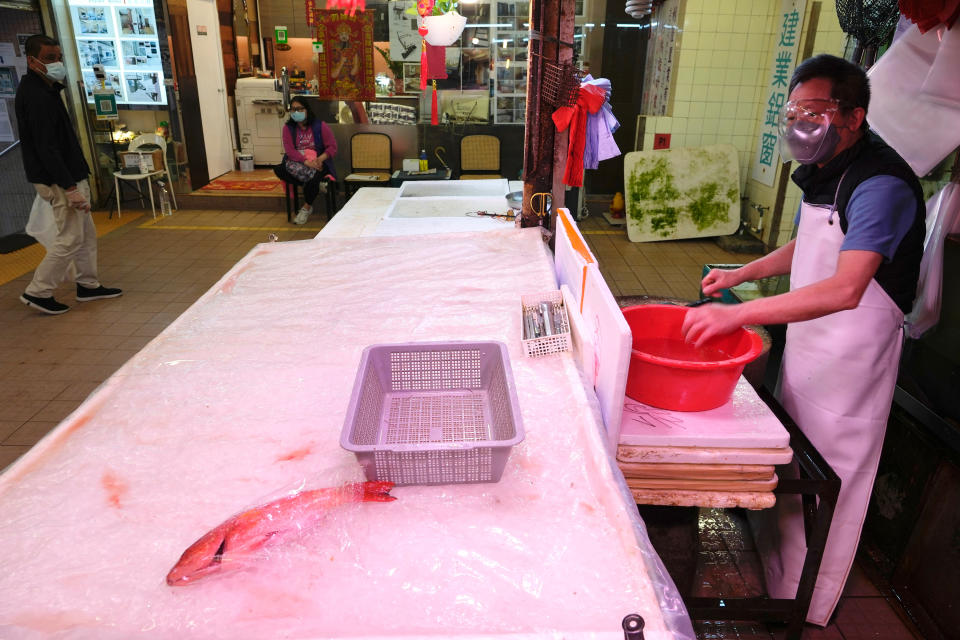 A fish monger stands at his stall with one remaining fish for sale as residents worry about a shortage of fresh food at a market in Hong Kong Monday, Feb. 28, 2022. Hong Kong on Monday reported a record-high 34,466 infections, with health authorities saying that a lockdown has not been ruled out as fatalities continued to climb. (AP Photo/Vincent Yu)