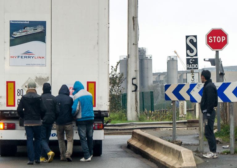 Immigrants wait behind a lorry at a stop sign in the northern French city of Calais, on October 24, 2014