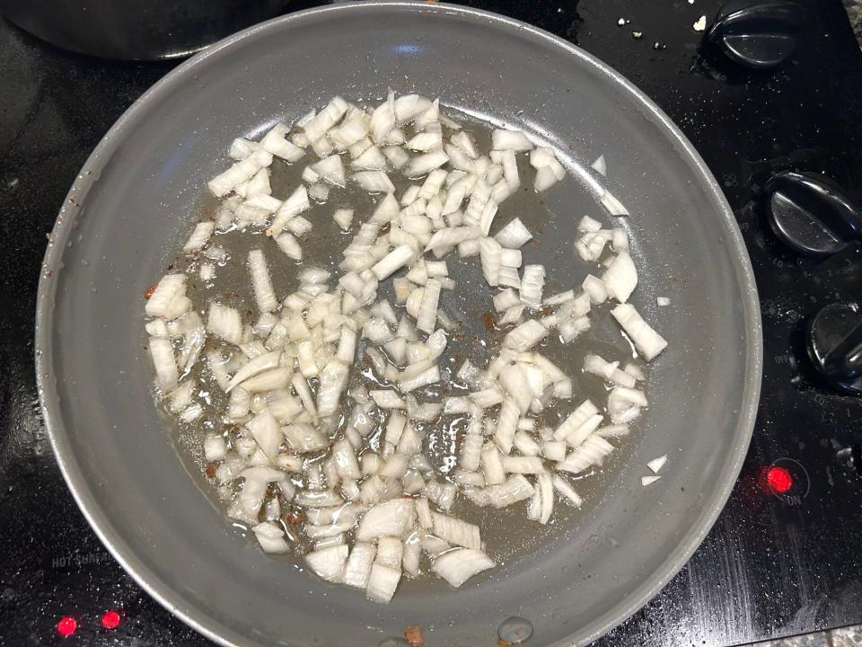 Adding onions to a pan for Giada De Laurentiis' Bucatini All'Amatriciana pasta