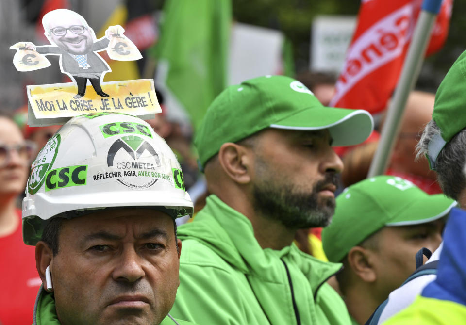 FILE - A man wears a hat with a photo of European Council President Charles Michel holding money bags which reads 'I am the crisis, I manage it' during a demonstration to protest against the rising cost of living in Brussels, on June 20, 2022. As food costs and fuel bills soar, inflation is plundering people’s wallets, sparking a wave of protests and workers’ strikes around the world. (AP Photo/Geert Vanden Wijngaert)