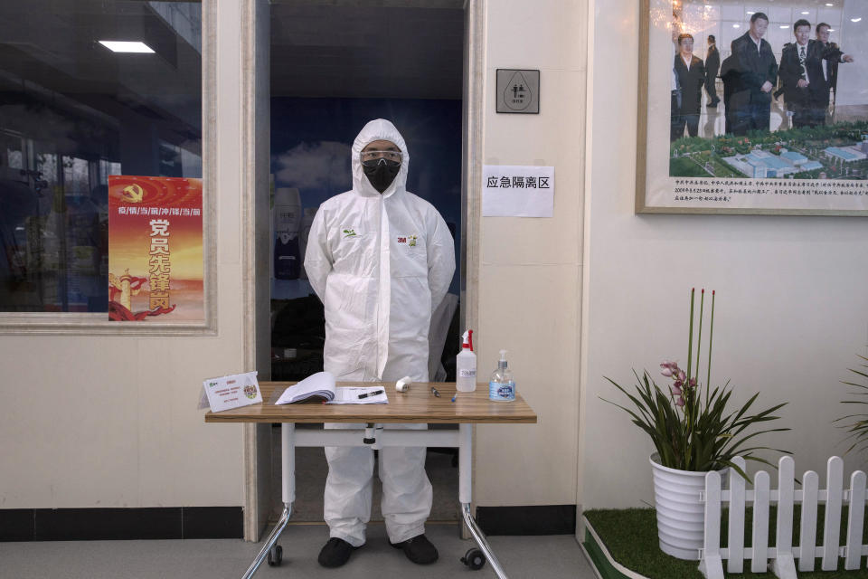 In this Thursday, Feb. 27, 2020, photo, a worker stands near a picture showing Chinese President Xi Jinping visiting the Mengniu dairy factory in Beijing. Reporters were invited to China Mengniu Dairy Co. Ltd. this week to be shown how companies are reviving after anti-virus measures shut down most of the world's second-biggest economy. (AP Photo/Ng Han Guan)