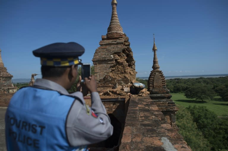 A police officer photographs damage at Htilominlo Temple in Myanmar's ancient city of Bagan on August 25, 2016 following a 6.8 magnitude earthquake