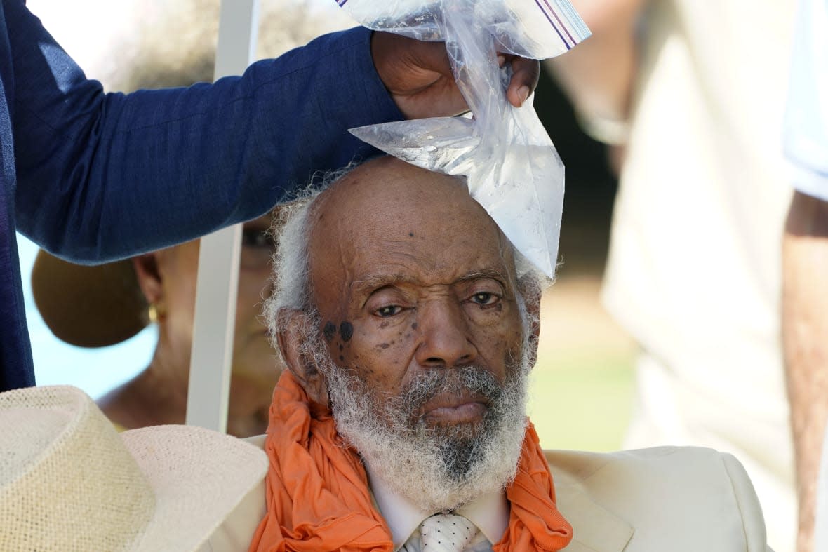 Political activist and writer James Meredith sits in the shade as an event staffer holds an ice pack on his head after he fell outside the Mississippi Capitol at an event marking his 90th birthday, in Jackson, Miss., Sunday, June 25, 2023. (AP Photo/Rogelio V. Solis)