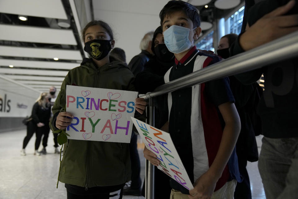 Children from the Mogul family, hold signs for their cousins as they wait for them to arrive on a flight from Charlotte, North Carolina, in the U.S., at Terminal 5 of Heathrow Airport in London, Monday, Aug. 2, 2021. Travelers fully vaccinated against coronavirus from the United States and much of Europe were able to enter Britain without quarantining starting today, a move welcomed by Britain's ailing travel industry. (AP Photo/Matt Dunham)