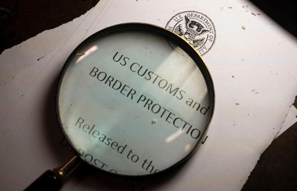 A magnifying glass is seen next to a logo of the Customs and Border Protection, Trade and Cargo Division at John F. Kennedy Airport's US Postal Service facility on June 24, 2019 in New York.