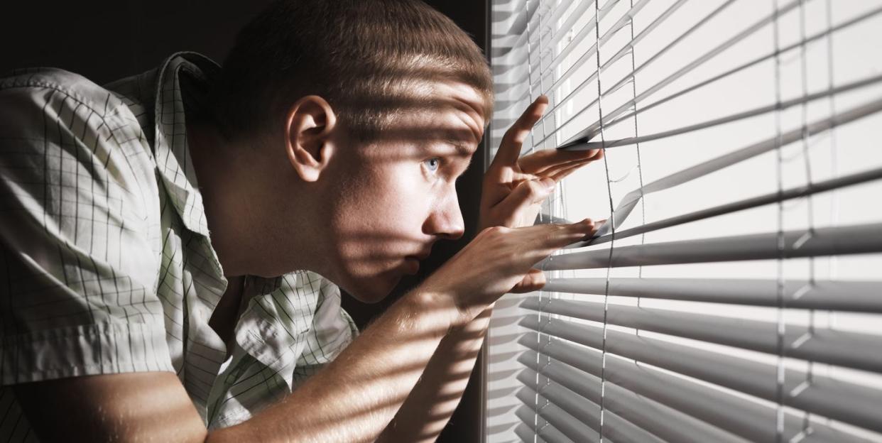 man looking through the blinds