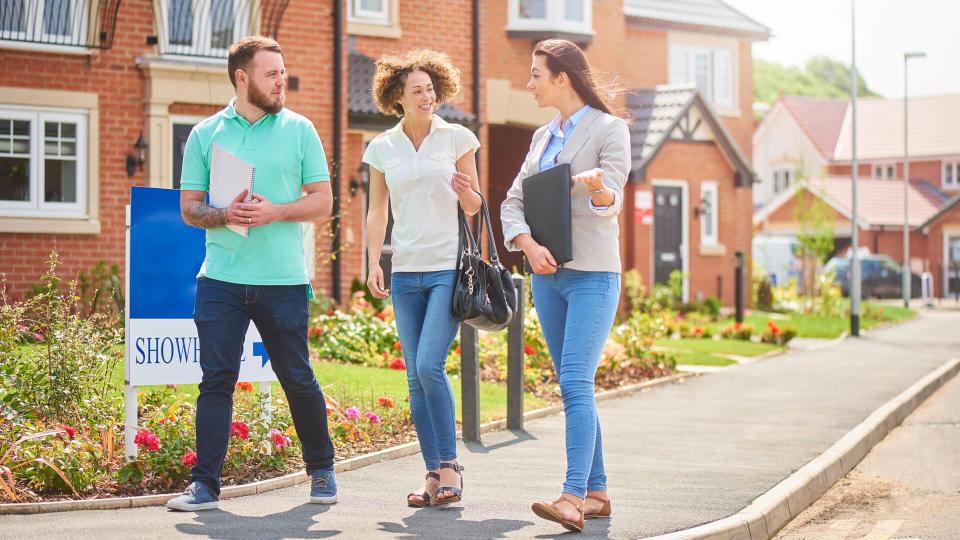 a mid adult couple browse a new housing development whilst listening to the sales assistant or estate agent  .