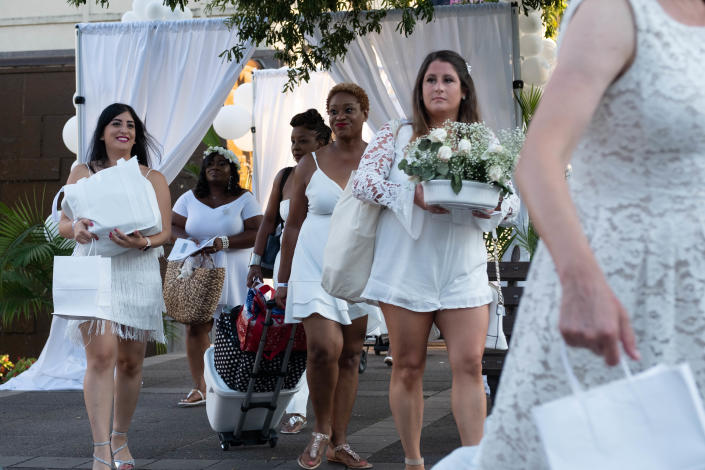 Guests carry food and table settings into Court Square in Memphis for the city's second annual Diner en Blanc in 2019.